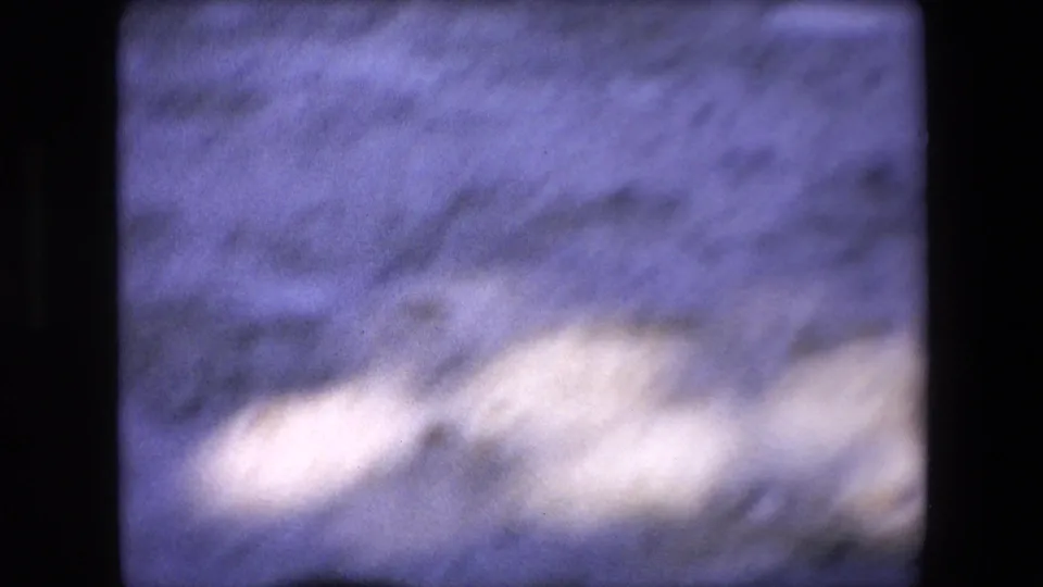 The final frame shows a soft, nearly abstract view of sandy arena ground with shadowed areas and bright exposure patches, consistent with handheld 8mm movement.