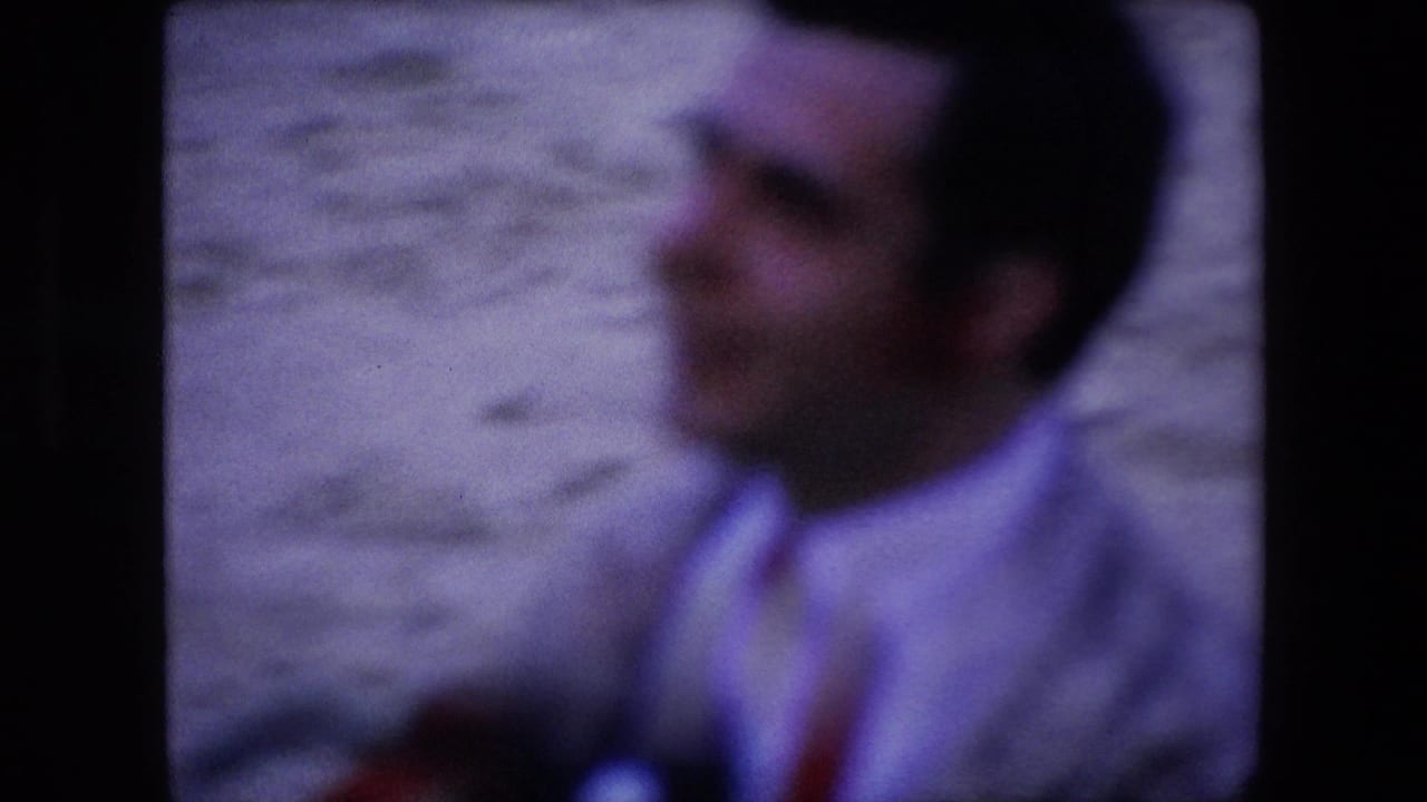 Blurred 1971 Barcelona frame of a man in a light shirt standing near a pale wall, with the home-movie focus drifting away from his face.