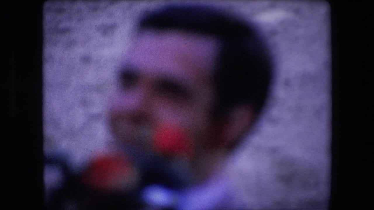 Soft-focus 1971 Barcelona home-movie frame showing a close, indistinct view of a man in front of a pale arena wall.