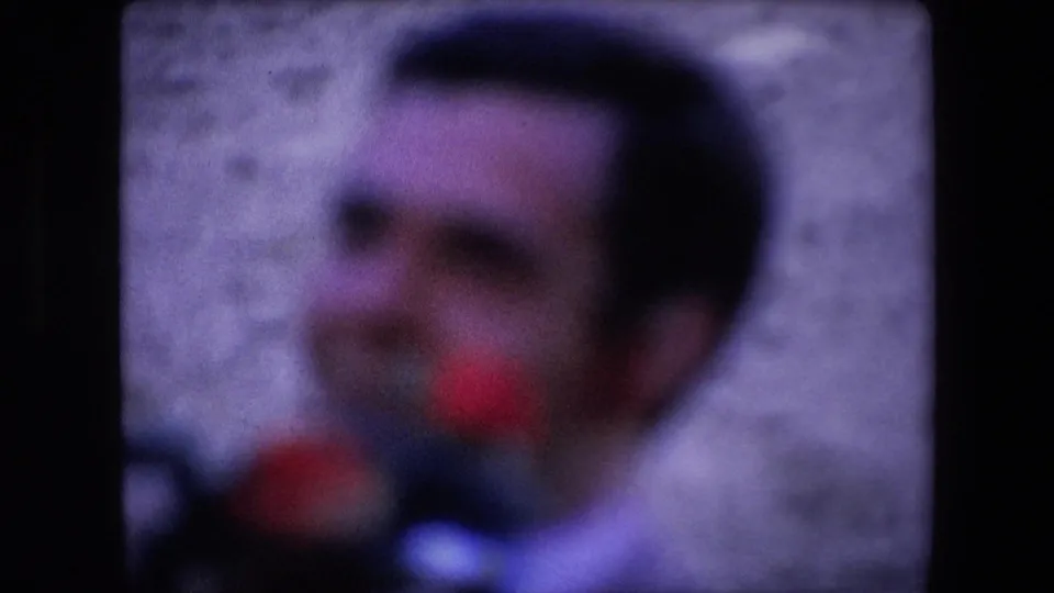 Soft-focus 1971 Barcelona home-movie frame showing a close, indistinct view of a man in front of a pale arena wall.