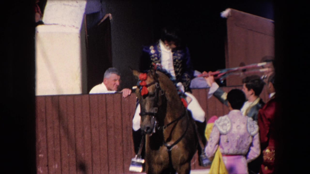 1971 Barcelona bullfight frame showing an ornate-costumed rider on a decorated horse near a wooden arena gate, with attendants and onlookers gathered close by.