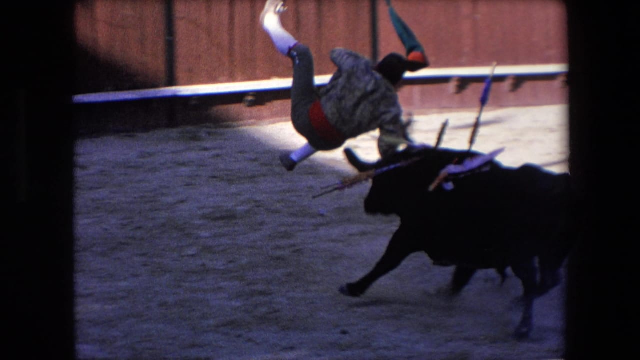 In the supplied 1971 Barcelona bullfight footage, a costumed bullfighter is thrown or flips over a charging black bull as equipment scatters in the ring.