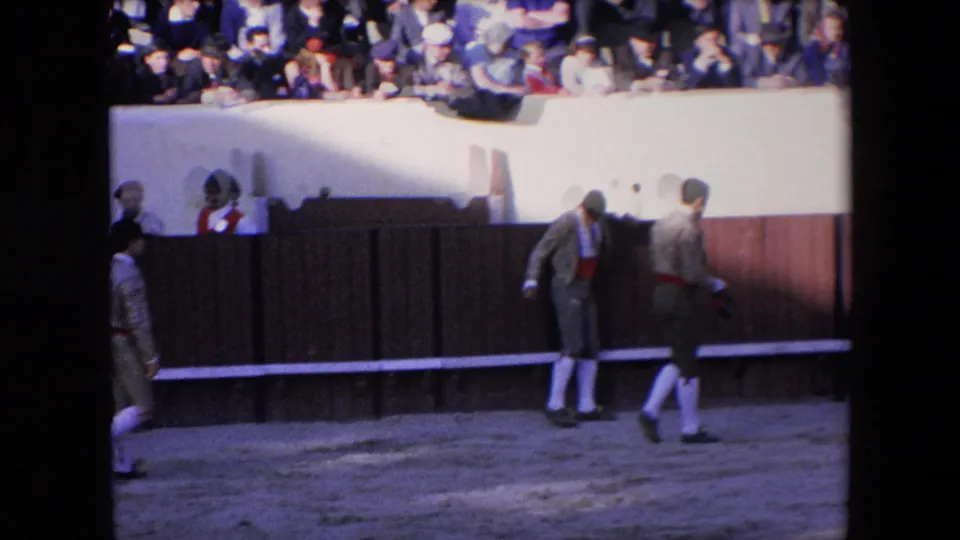 1971 Barcelona 8mm frame showing matador or arena figures near a wooden barrier with spectators seated above the bullring wall.