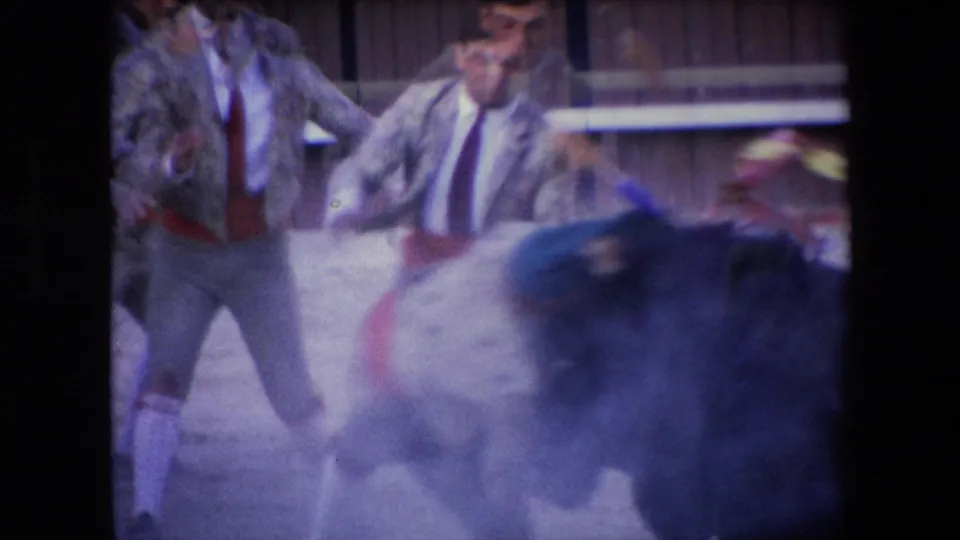 The bull charges close to the matador in the 1971 Barcelona arena footage, with motion blur obscuring some details of the encounter.