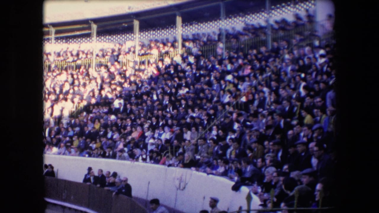 1971 Barcelona home-movie view of densely packed bullring seating, with spectators filling tiered stands above a white arena wall.