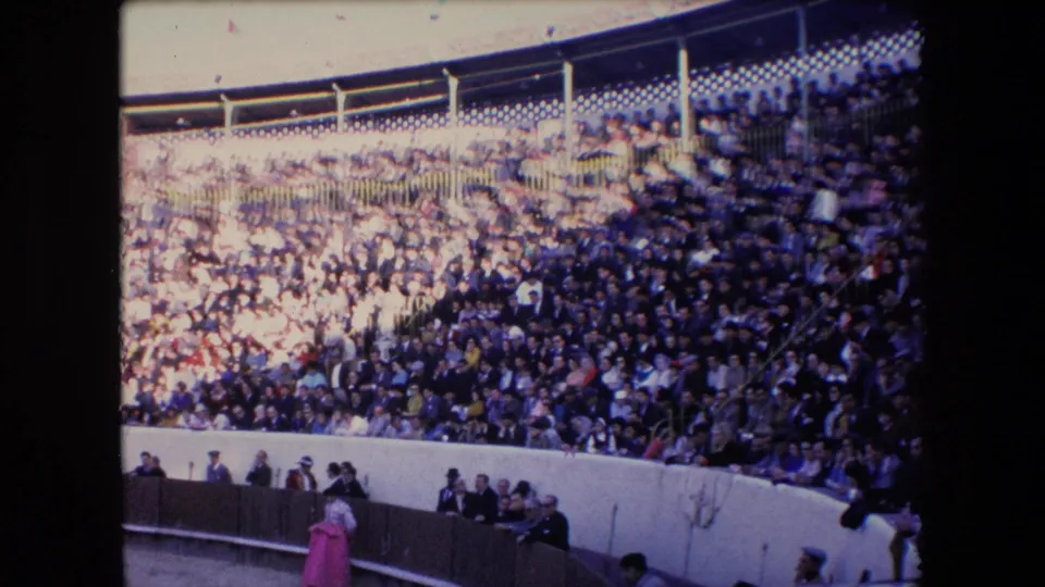 1971 Barcelona 8mm frame showing the packed bullring stands and a pink-costumed figure near the barrier in the ring area.
