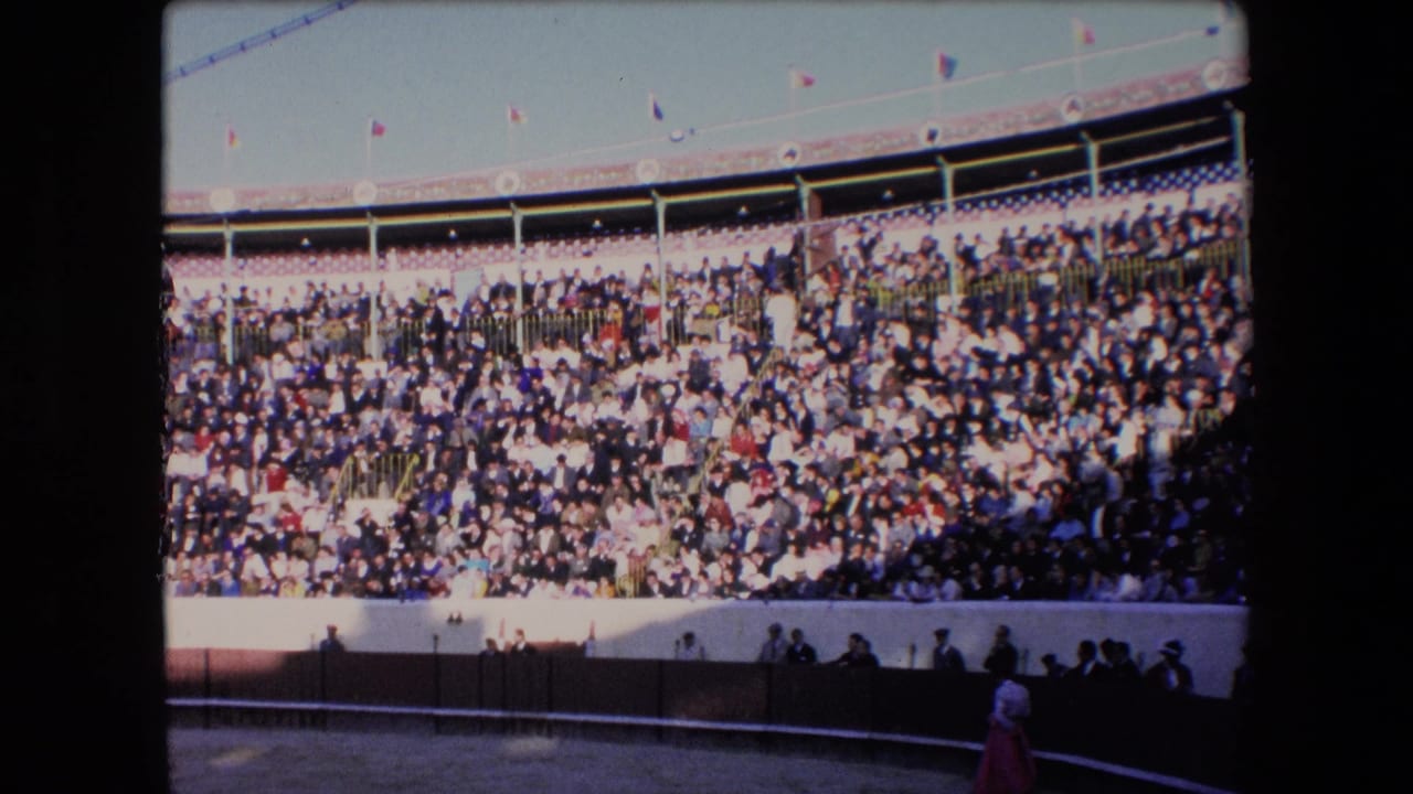Barcelona bullring spectators in 1971 fill the sunlit stands while a matador with a cape stands near the arena edge in 8mm footage.