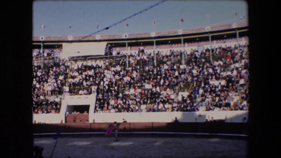 The 1971 Barcelona bullfight footage shows a matador near the lower left of the arena with packed spectator stands behind him.