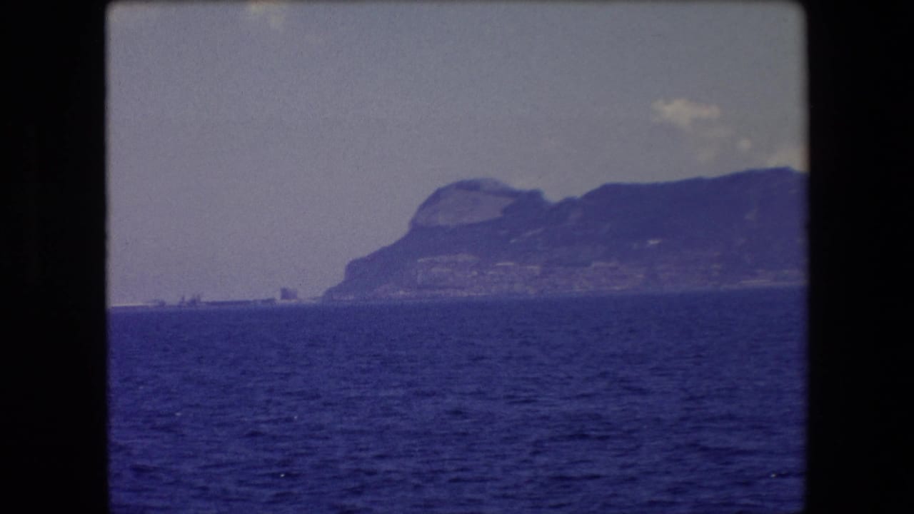 Blue sea with a distant mountainous coastline under a pale sky.