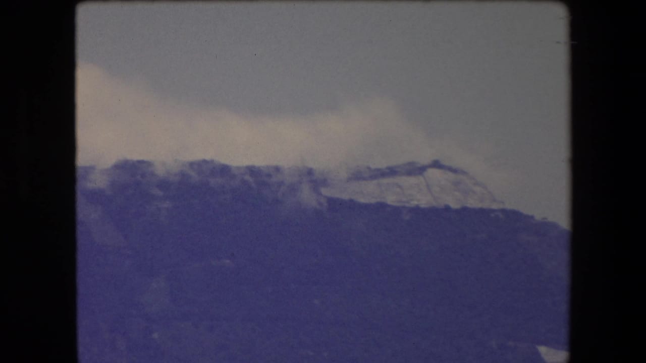 Cloudy sky above a dark mountain slope with a pale upper ridge.