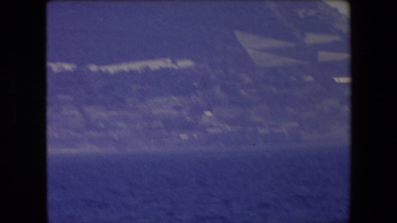 Soft, hazy view of coastline above dark blue water.