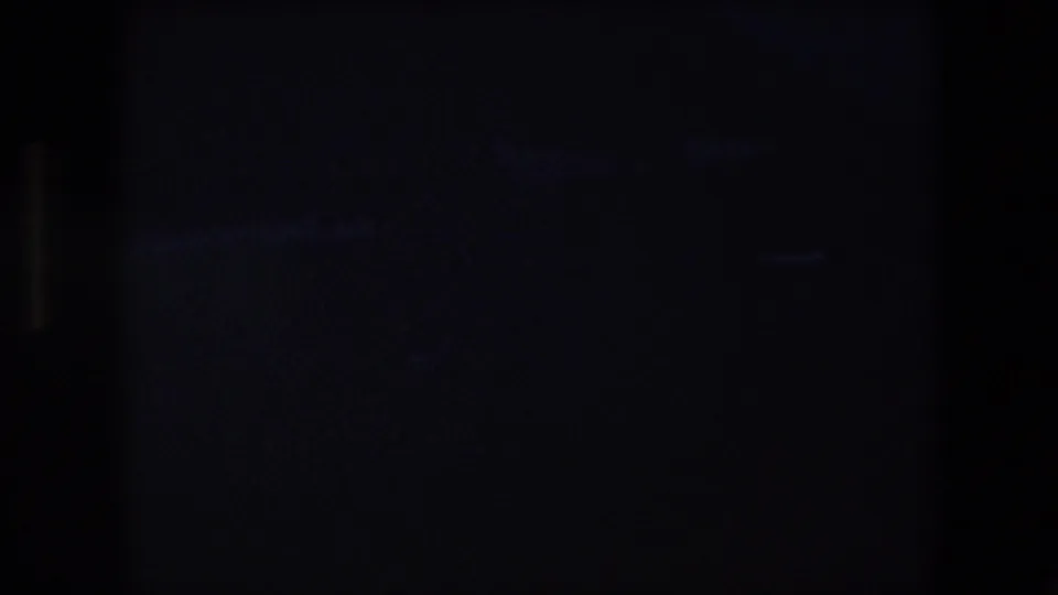 Underexposed final 8mm frame with mostly dark detail and faint structural or rigging-like shapes, requiring review against the moving footage for identification.
