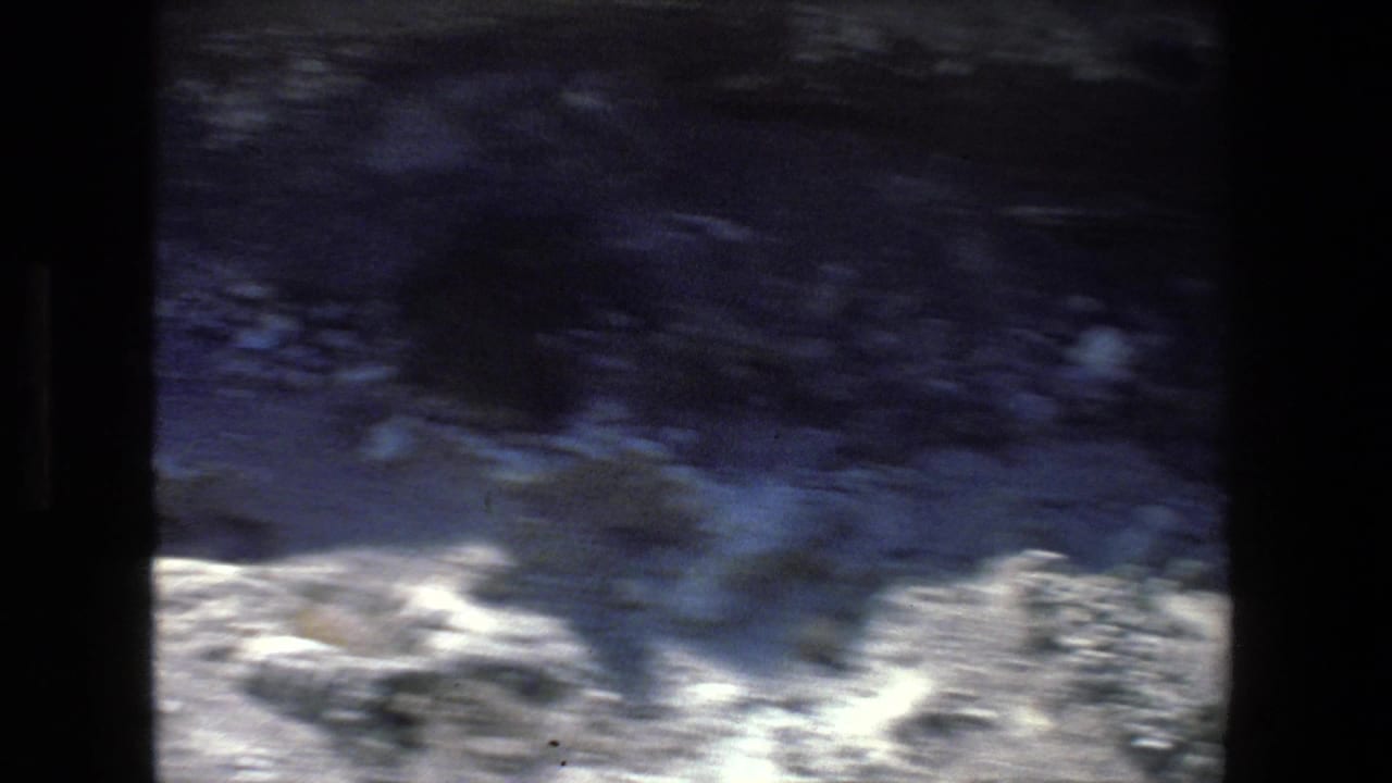 Blurred rocky hillside and shadowed foreground during a handheld pan.