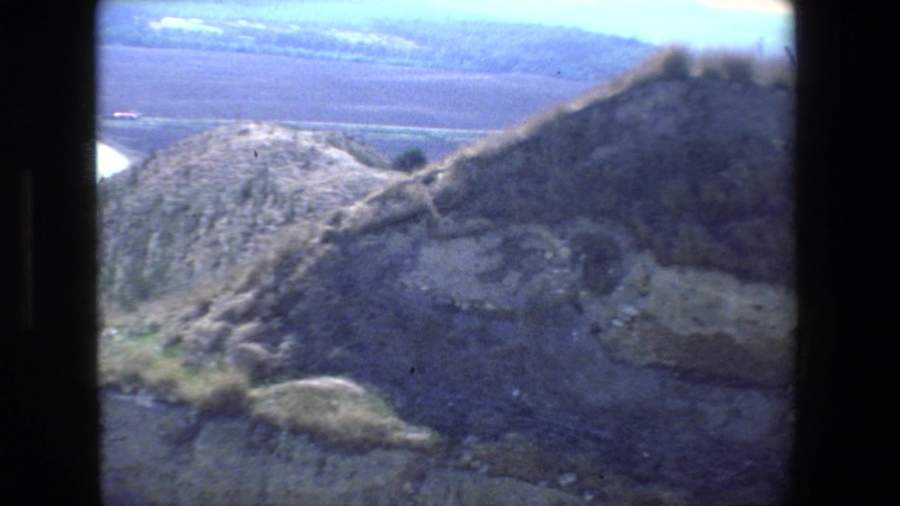 Rugged sunlit hills and a wide distant valley appear in this 1972 8mm Tel Aviv, Israel home-movie frame, with dark gate-edge framing at the sides.