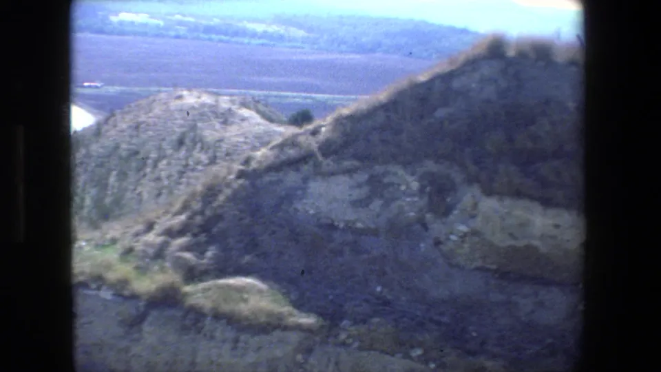 Rugged sunlit hills and a wide distant valley appear in this 1972 8mm Tel Aviv, Israel home-movie frame, with dark gate-edge framing at the sides.