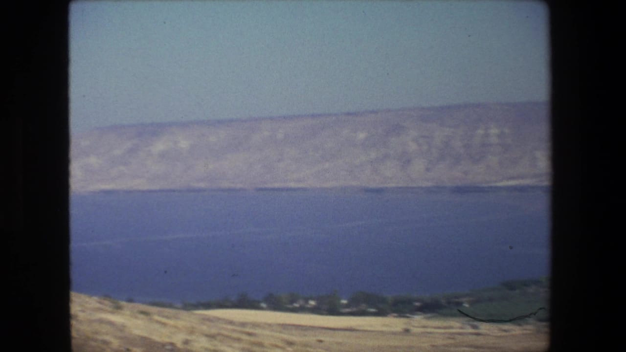 Wide view of blue water, dry hills, and distant shoreline under a clear sky.