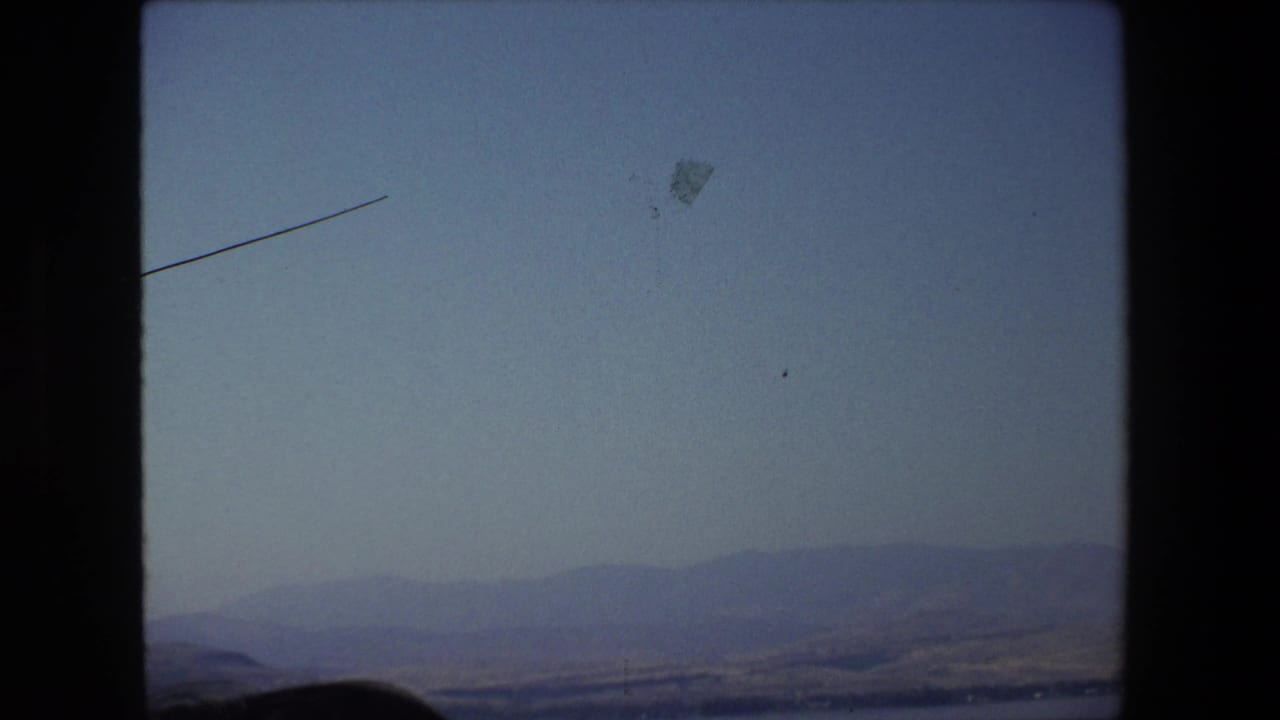 1972 Tel Aviv, Israel 8mm frame showing a hazy waterside landscape with distant hills, pale sky, and visible home-movie film borders.