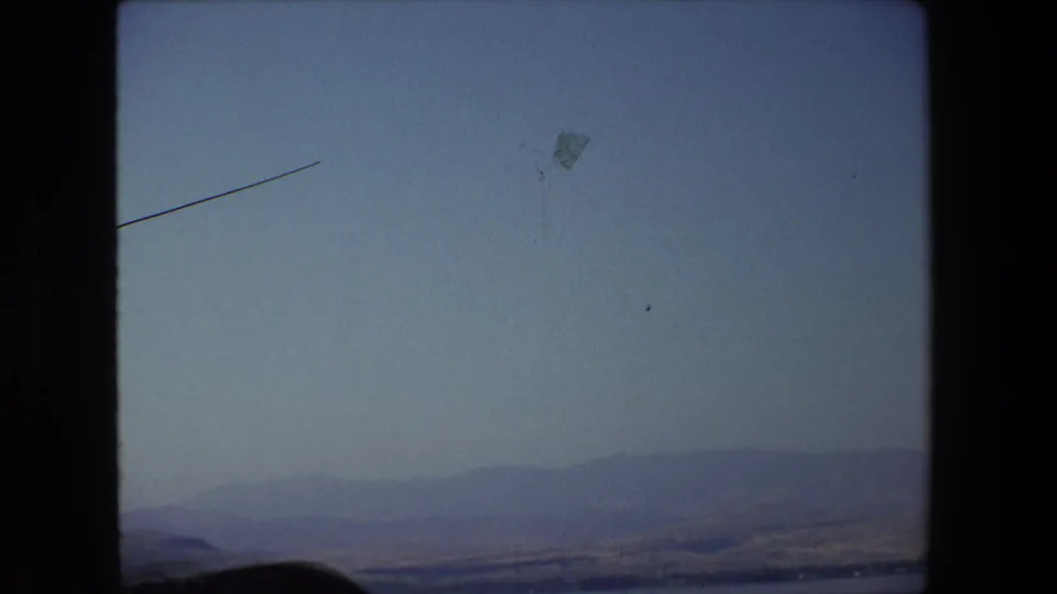1972 Tel Aviv, Israel 8mm frame showing a hazy waterside landscape with distant hills, pale sky, and visible home-movie film borders.