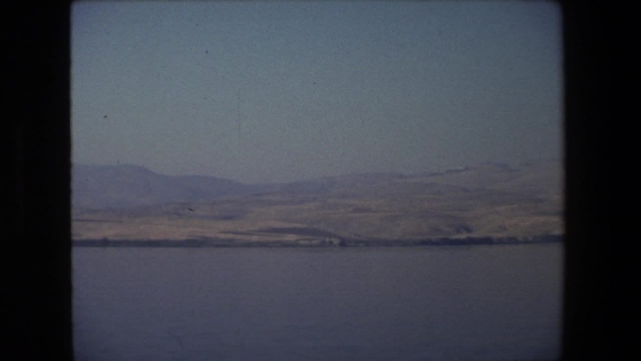 Broad water surface with low hills and a pale sky in the distance.