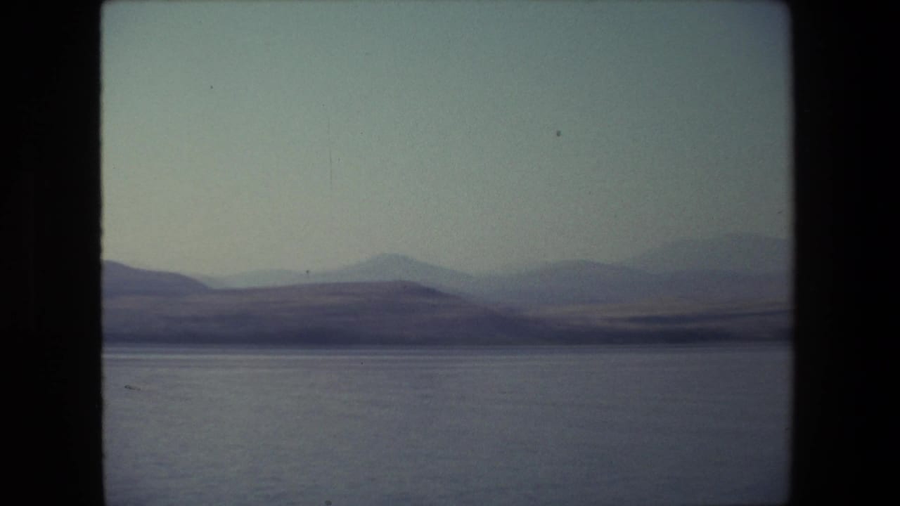 1972 Israel 8mm frame showing calm open water and distant hazy hills under a pale sky, with no people visible in this frame.