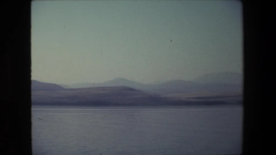 1972 Israel 8mm frame showing calm open water and distant hazy hills under a pale sky, with no people visible in this frame.