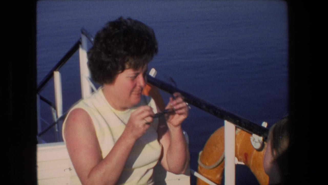 Woman seated on a boat holding eyeglasses near blue water.