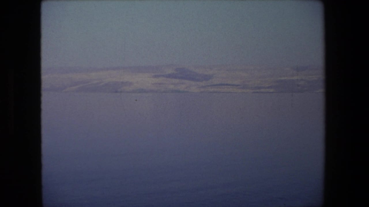 Hazy shoreline ridge seen across a broad expanse of blue water.