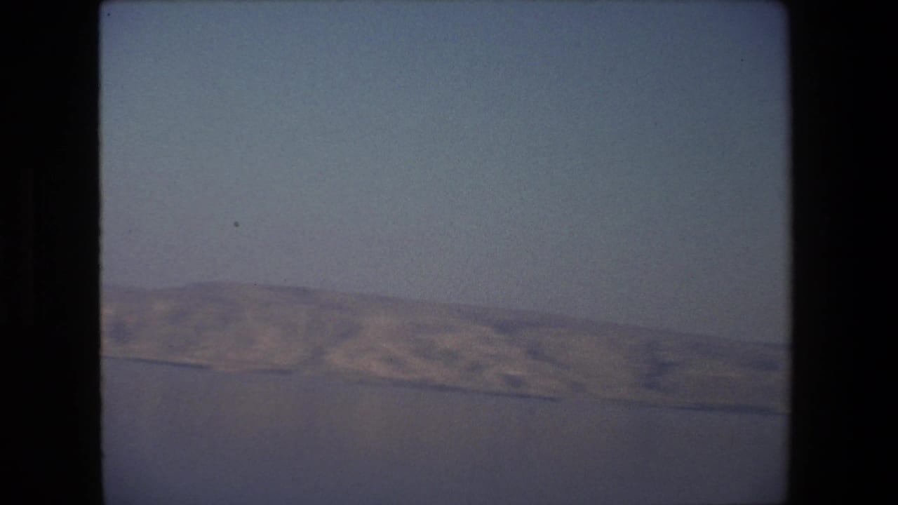 1972 Tel Aviv, Israel home-movie still with a slightly tilted composition, pale sky above, and a distant shoreline and hills along the lower frame.