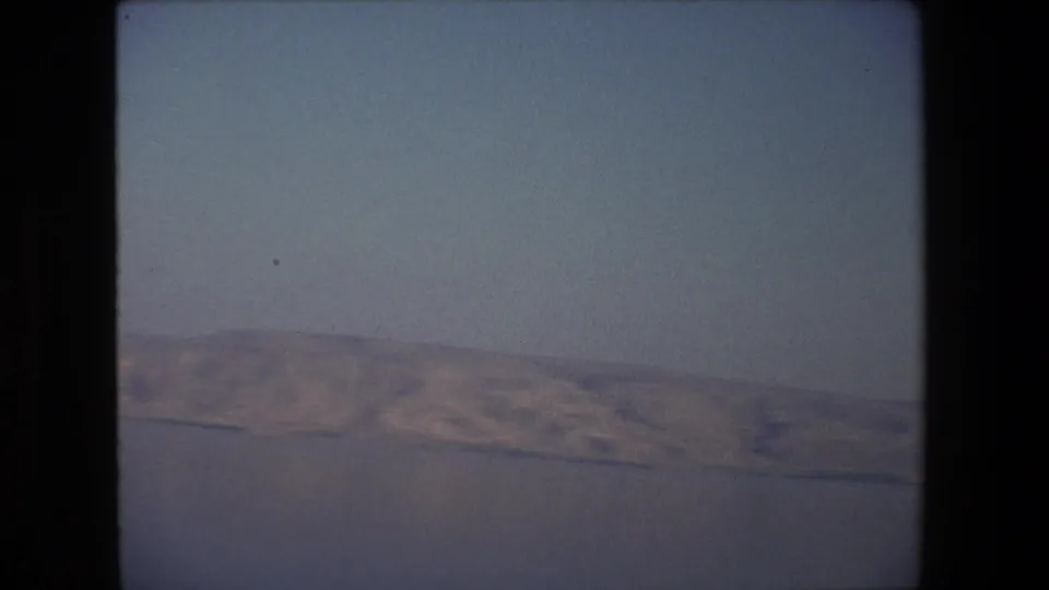1972 Tel Aviv, Israel home-movie still with a slightly tilted composition, pale sky above, and a distant shoreline and hills along the lower frame.