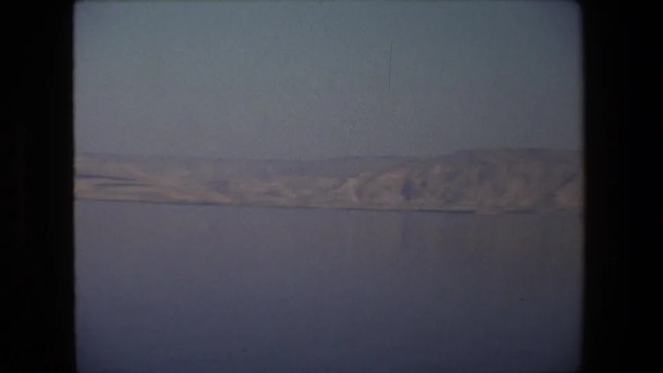 1972 Tel Aviv-area 8mm frame showing still water and a distant pale shoreline under a muted sky, with no people or buildings visible.