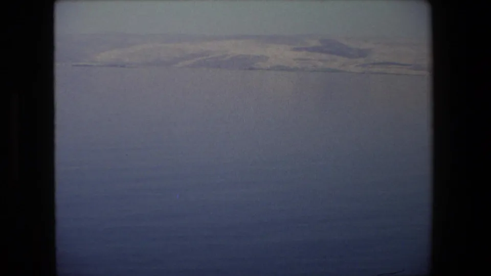 A soft, hazy opening view over water or distant landscape in 1972 Israel travel footage, framed with dark film edges.