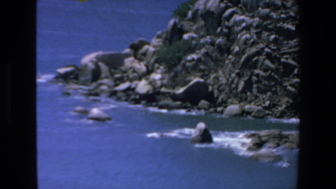 Rocky coastline and blue water with the parachute mostly out of frame.