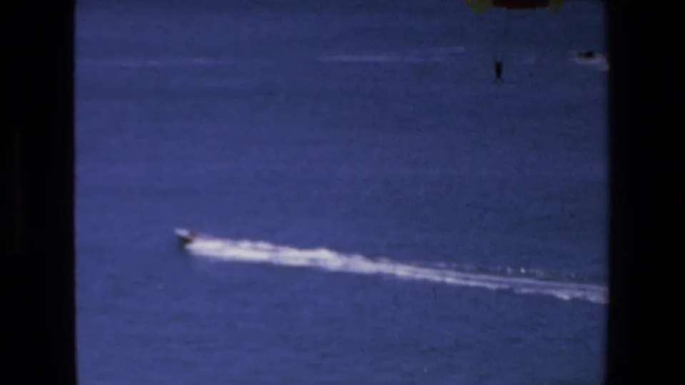 A small speedboat travels across blue water in the Mazatlan 1972 footage, with its long white wake framed by dark 8mm gate edges.
