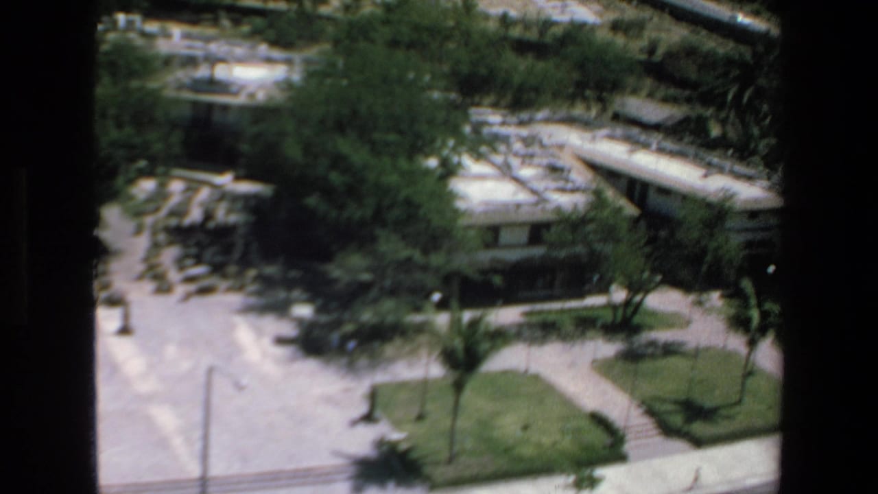 1972 Mazatlan home-movie frame looking down from a high vantage point over hotel grounds, roads, greenery, and palm trees.