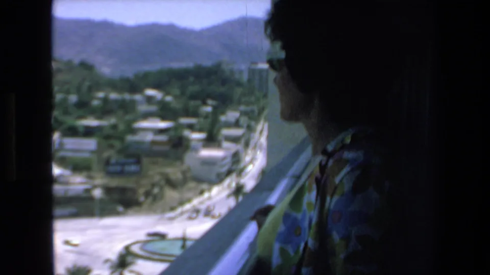 A closer, darker profile of the woman in sunglasses and a floral shirt appears beside the elevated view of Mazatlan streets, buildings, and mountains.