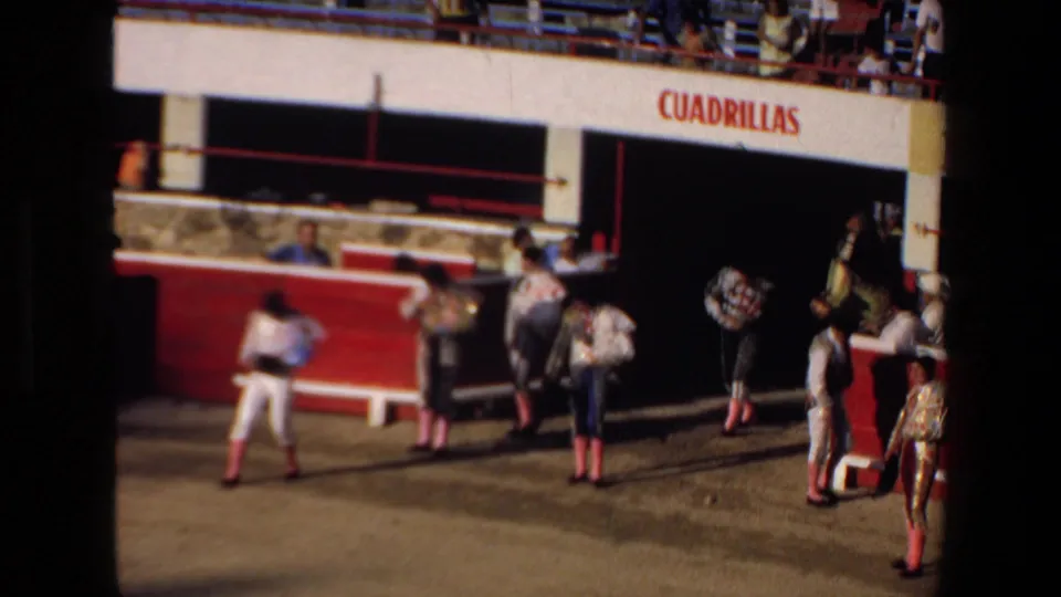 1972 Mazatlan bullring frame showing bullfighters in traditional clothing near the CUADRILLAS tunnel, with red barriers and spectators above.