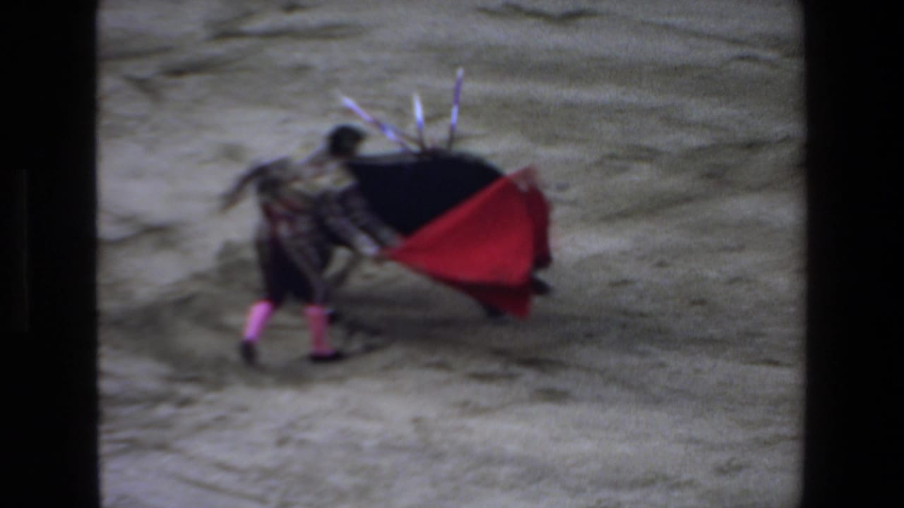 Black bull charges near a matador extending a red cape.