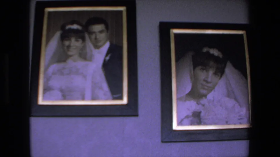 The final frame holds on framed wedding portraits, with a bride and groom portrait beside a close bridal portrait on an interior wall.