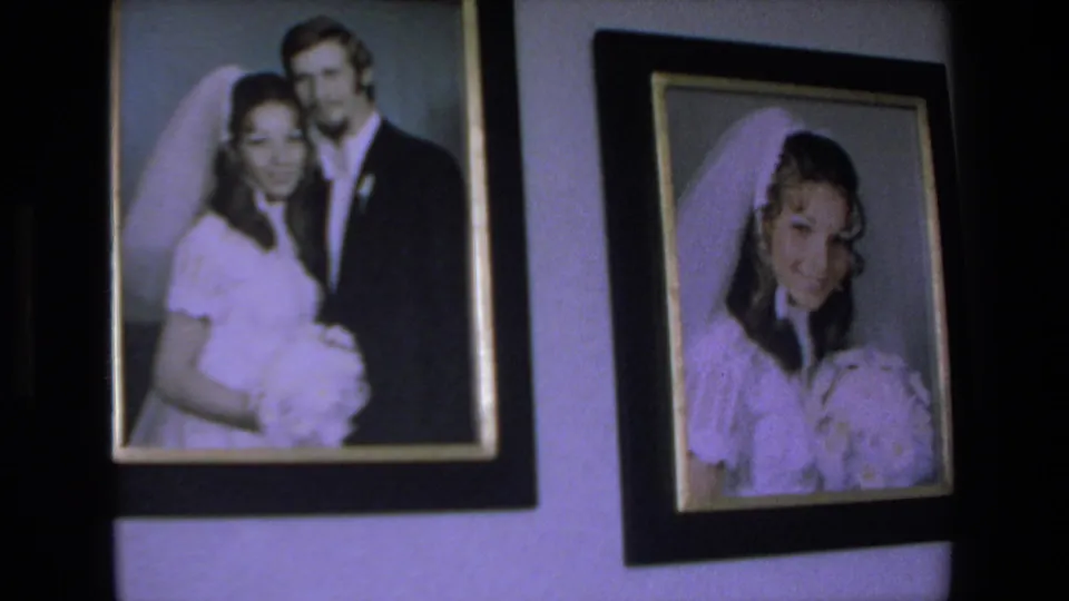 Two framed wedding photographs appear on a wall, one showing a bride and groom together and the other showing the bride holding flowers.