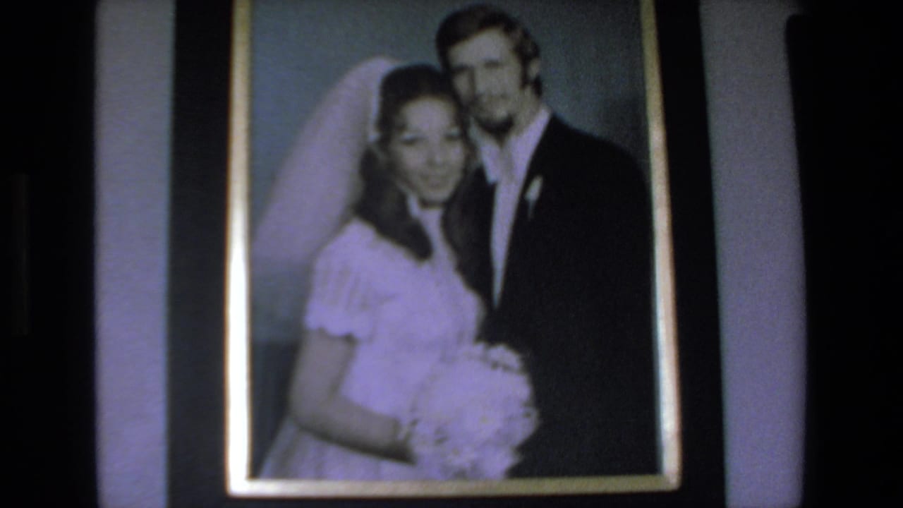 Framed wedding photograph showing a bride in a white dress and veil beside a groom in a dark suit, from 1972 Mazatlan home-movie footage.