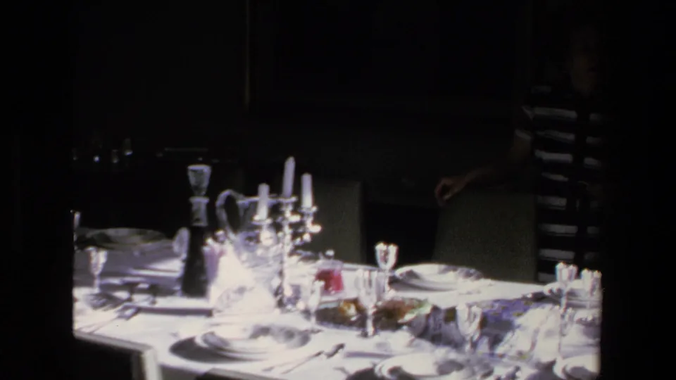 A woman in a black and white striped dress stands beside the formal dinner table in this 1972 Mazatlan home-movie interior.