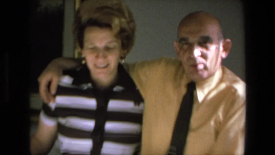 A closer 8mm frame shows the man with his arm around the woman’s shoulder as they face the camera in the private Mazatlan dining-room setting.