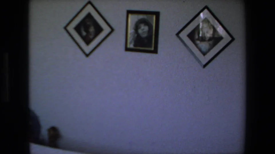 A textured interior wall in the Mazatlan home displays framed portraits and diamond-shaped wall art, with dark doorway edges and soft 8mm exposure.