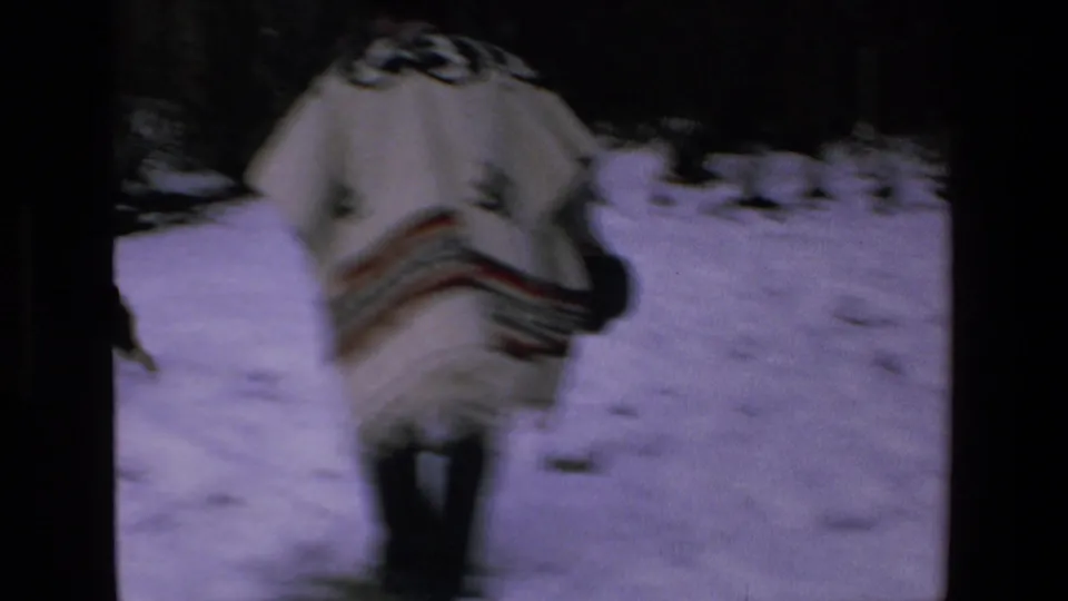 A back view shows the man in a white poncho with dark geometric patterning moving across snowy ground in the supplied 1972 Mazatlan home-movie clip.