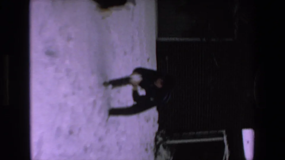 A dark-clothed person stands or moves across a snow-covered yard with a small dog nearby, seen in soft 1970s 8mm home-movie footage labeled Mazatlan, Mexico.