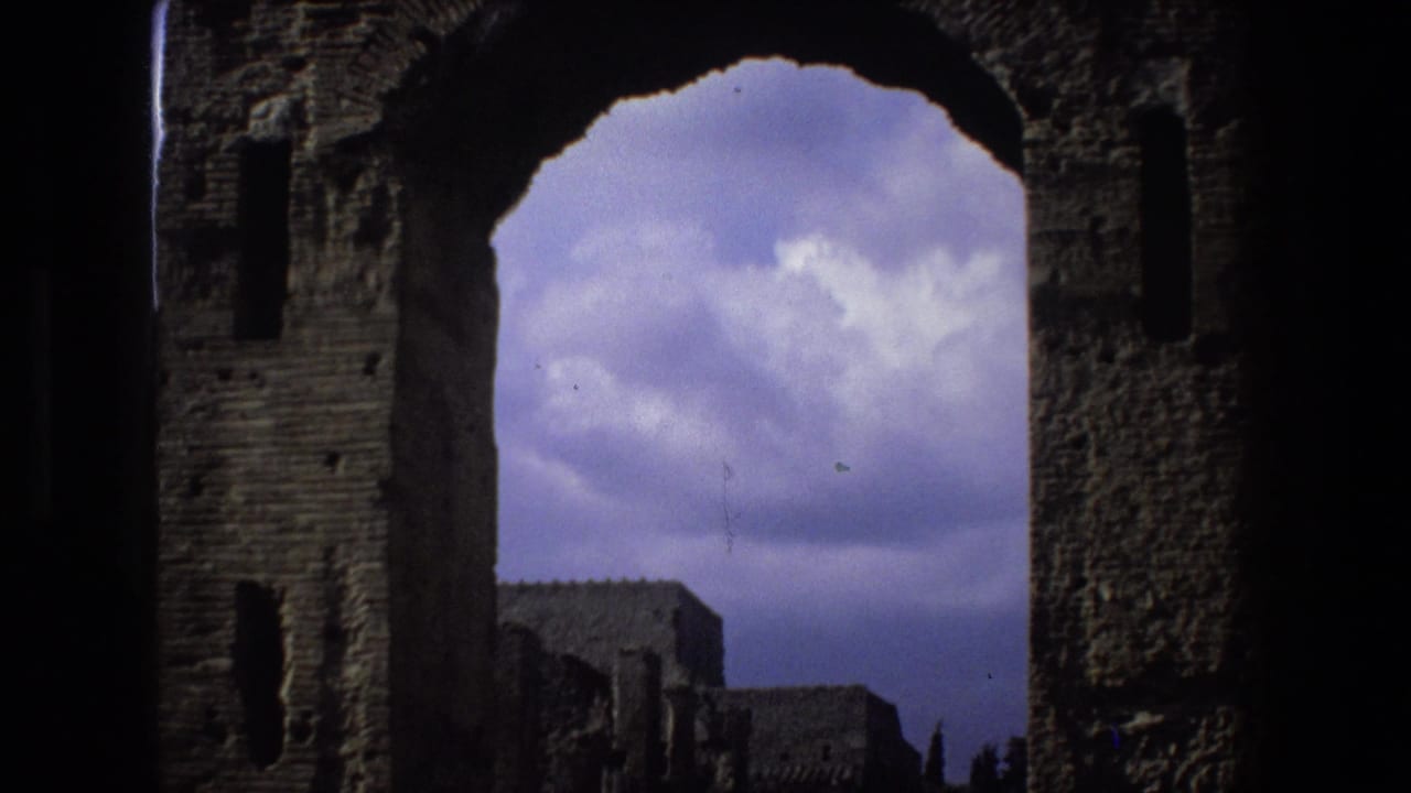 Weathered archway with clouds and distant stone structures beyond.