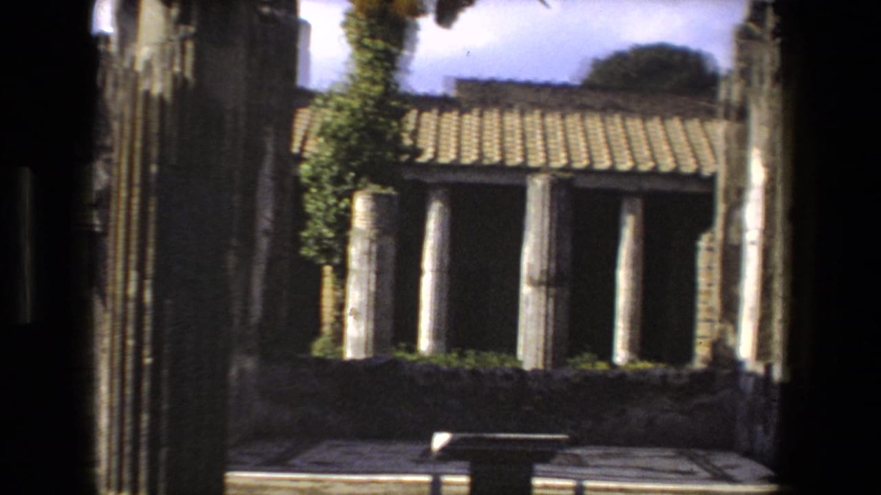 Sunlit stone columns and tiled roof seen through a dark doorway.
