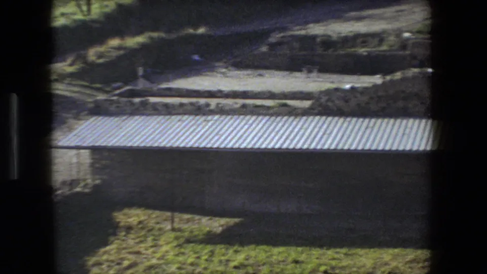 Rome, Italy 1973 home-movie view of a long corrugated roof set below terraced earth and stonework at a historic excavation area.