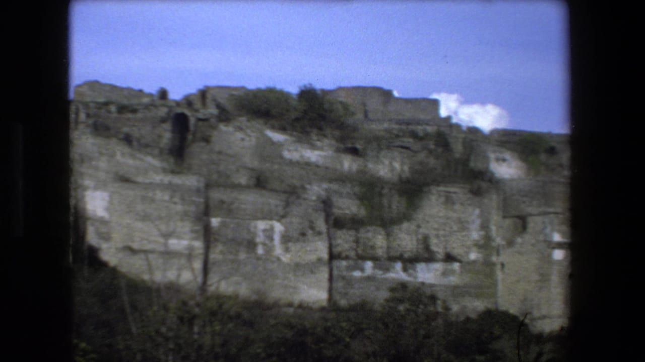 Weathered stone wall and hillside ruins under a clear sky.