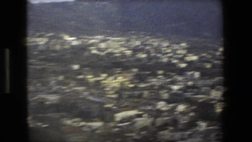 Final 8mm frame with a soft, blue-gray view of clustered hillside buildings in the Rome, Italy coastal setting, heavily blurred by motion.